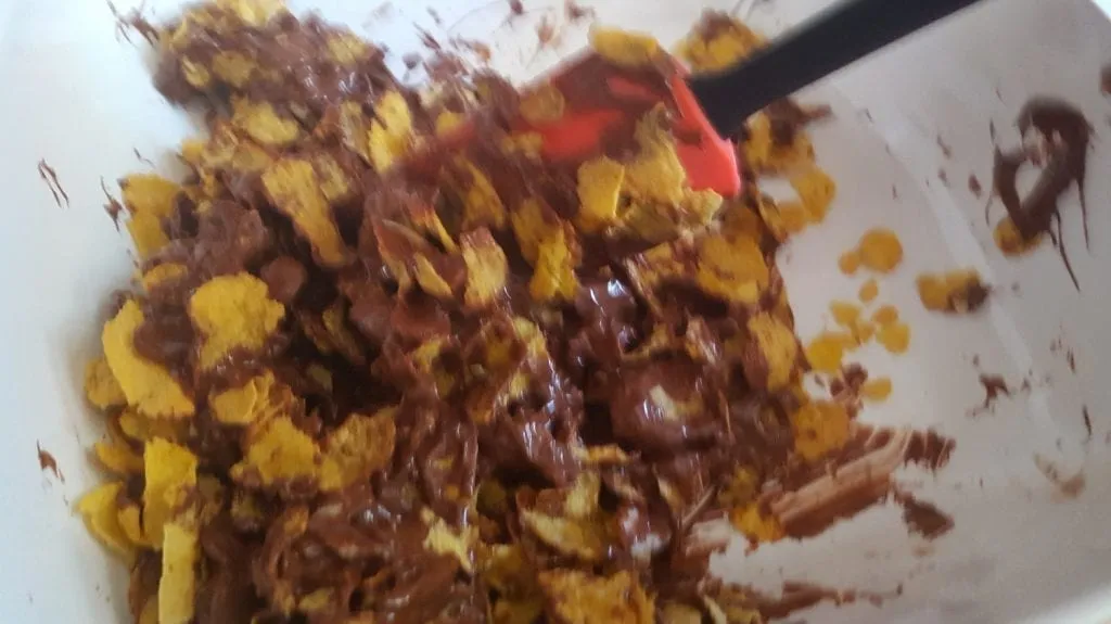 Mischung für Schoko Crossies: Cornflakes und Mandeln werden gleichmäßig mit Schokolade verrührt.