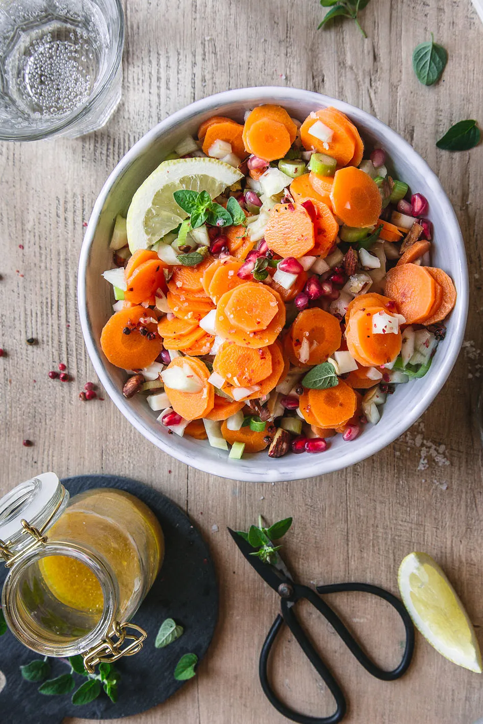 Möhren-Fenchel-Salat in weißer Schüssel mit Dressing in Flasche