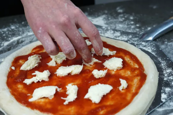 Mozzarella in groben Stücken auf der Pizza verteilen
