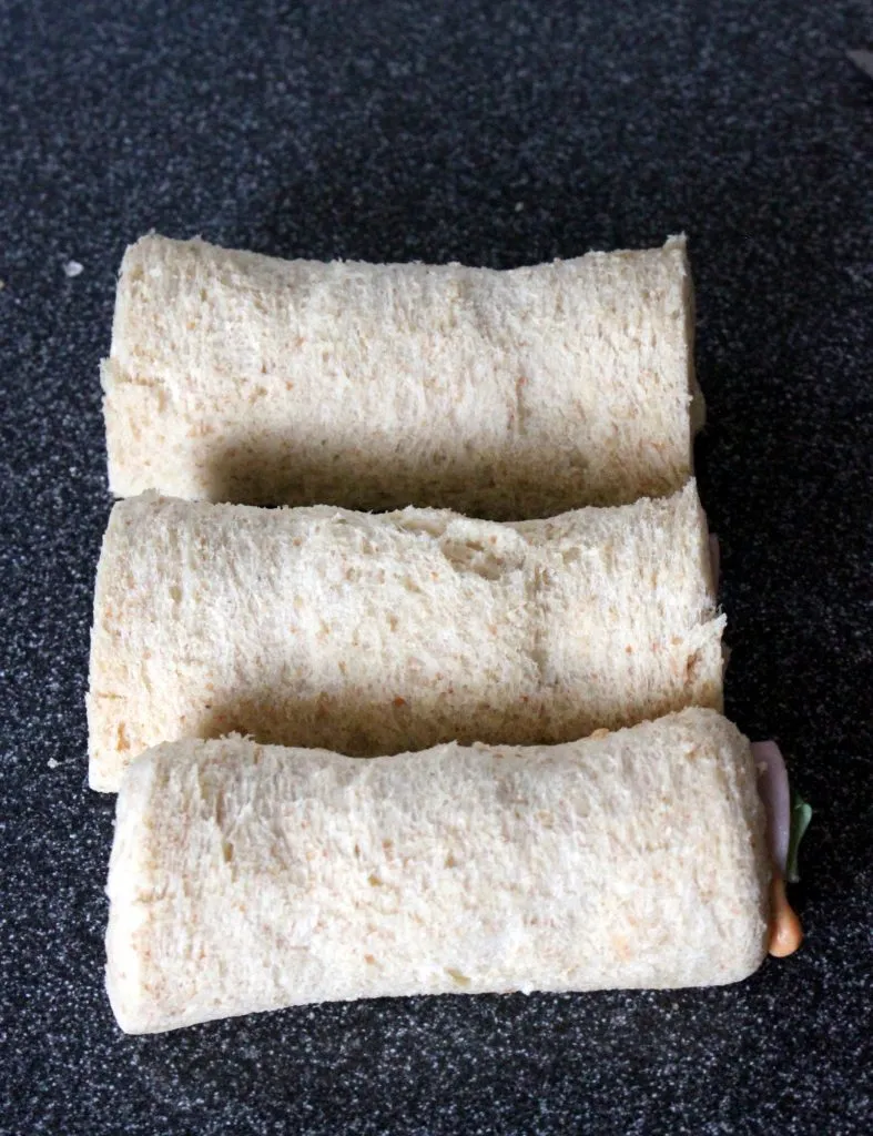 Mozzarella-Käsestange und frische Basilikumblätter auf dem Schinken bereit zum Einrollen