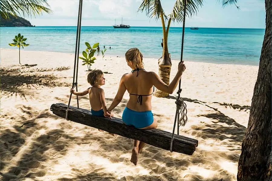 Mutter und Kind genießen einen entspannten Billigurlaub am Strand in einer Hängematte