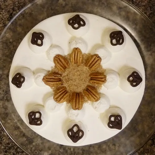 Nahaufnahme der cremigen Sahneschicht auf einem Tortenboden, mit sichtbaren Nussstückchen