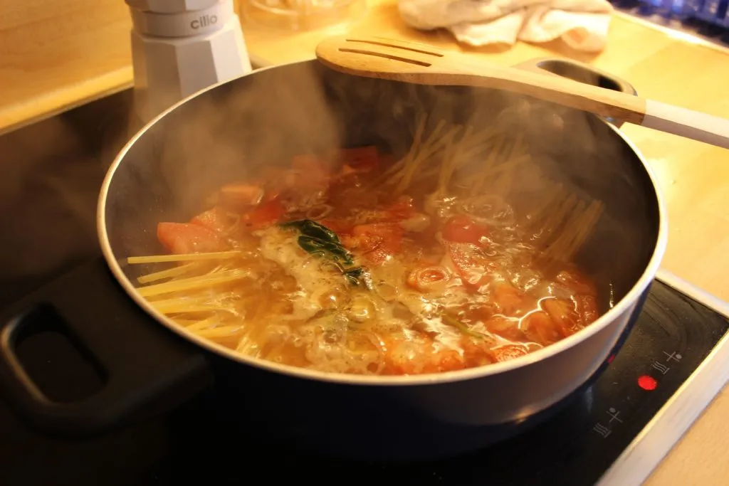 Nahaufnahme der frischen Zutaten wie Tomaten, Zwiebeln und Linguine vor dem Kochprozess