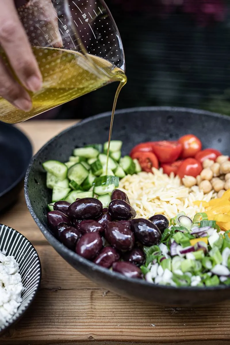 Nahaufnahme des Orzo Nudelsalats mit Feta, Oliven und frischen Kräutern, ein gesundes Gericht mit Schafskäse