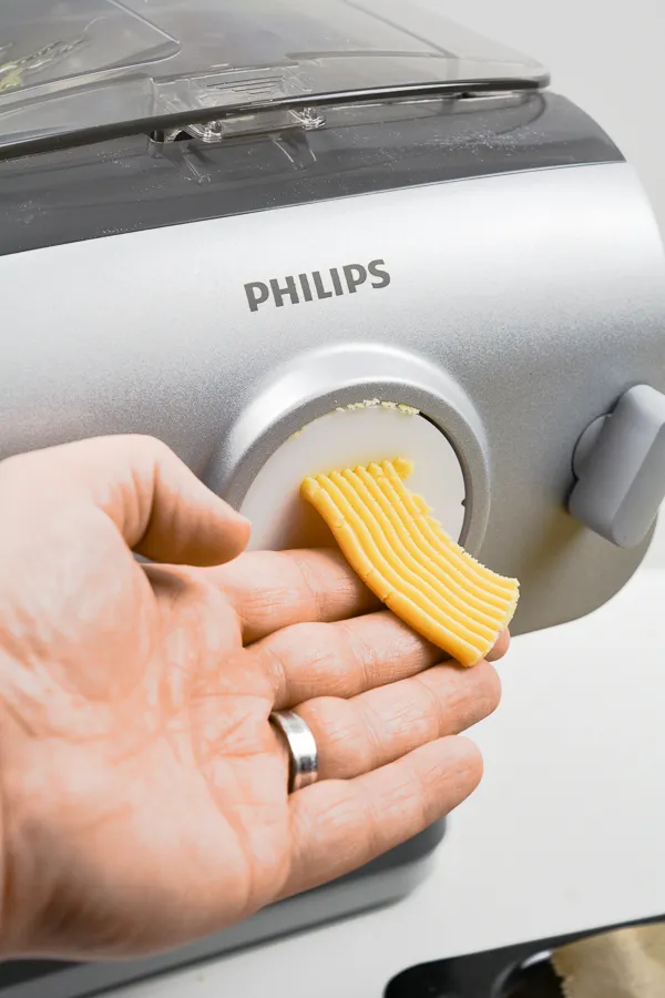 Nahaufnahme des Philips Pastamakers, der Spritzgebäck-Teigstränge perfekt durch den speziellen Aufsatz presst
