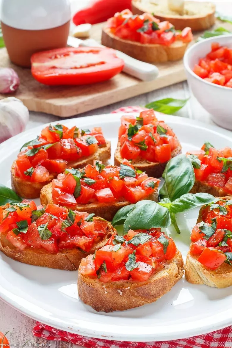 Nahaufnahme einer Bruschetta mit Tomaten und Basilikum, die gerade gegessen wird