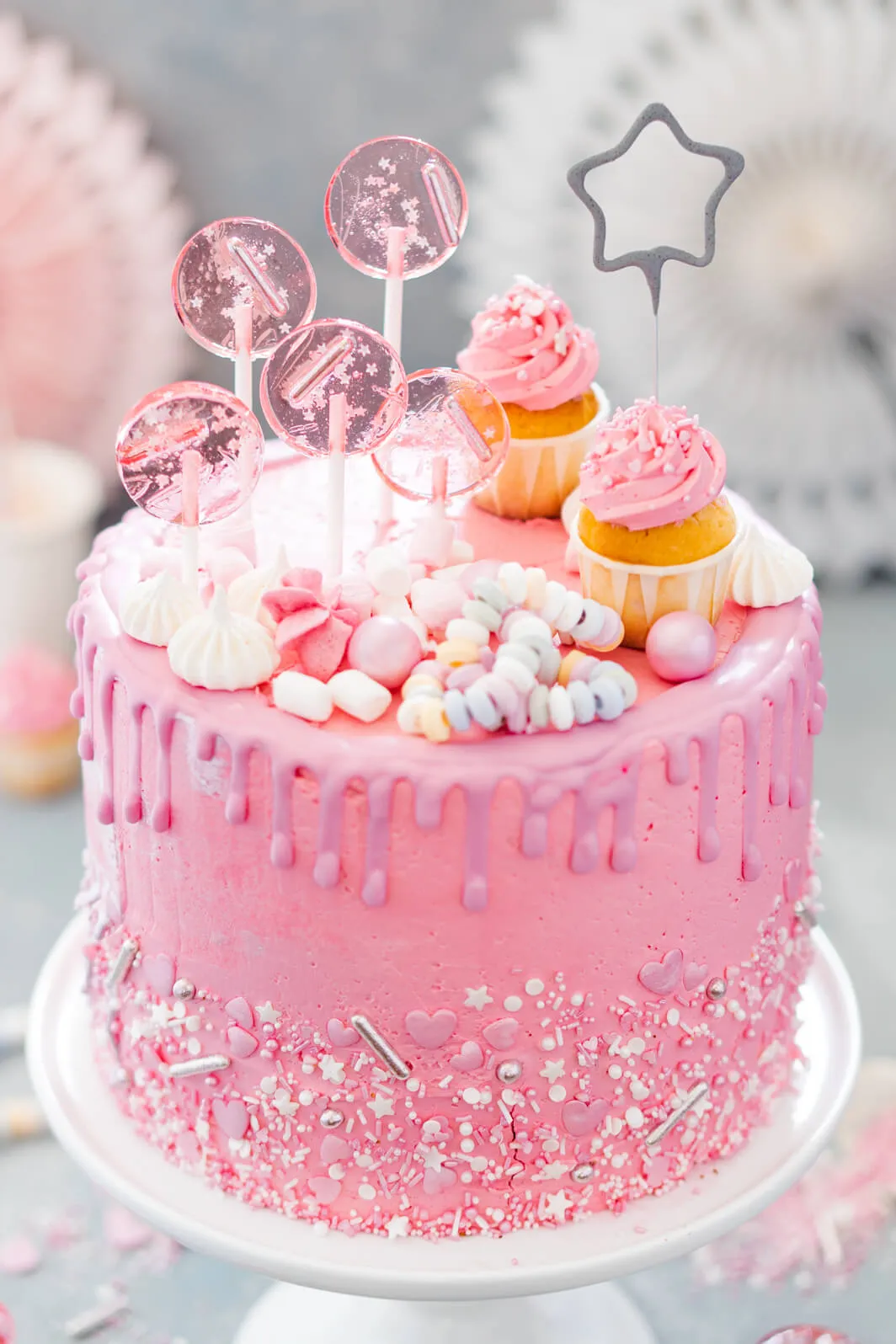 Nahaufnahme einer Drip Cake Schicht, reich verziert mit Beeren und bunten Lollies, die Frische und Festlichkeit ausstrahlt.