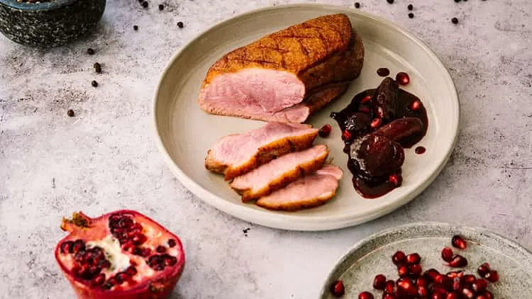 Nahaufnahme einer Entenbrust, deren Haut kunstvoll eingeritzt wird, um das Fett auszulassen