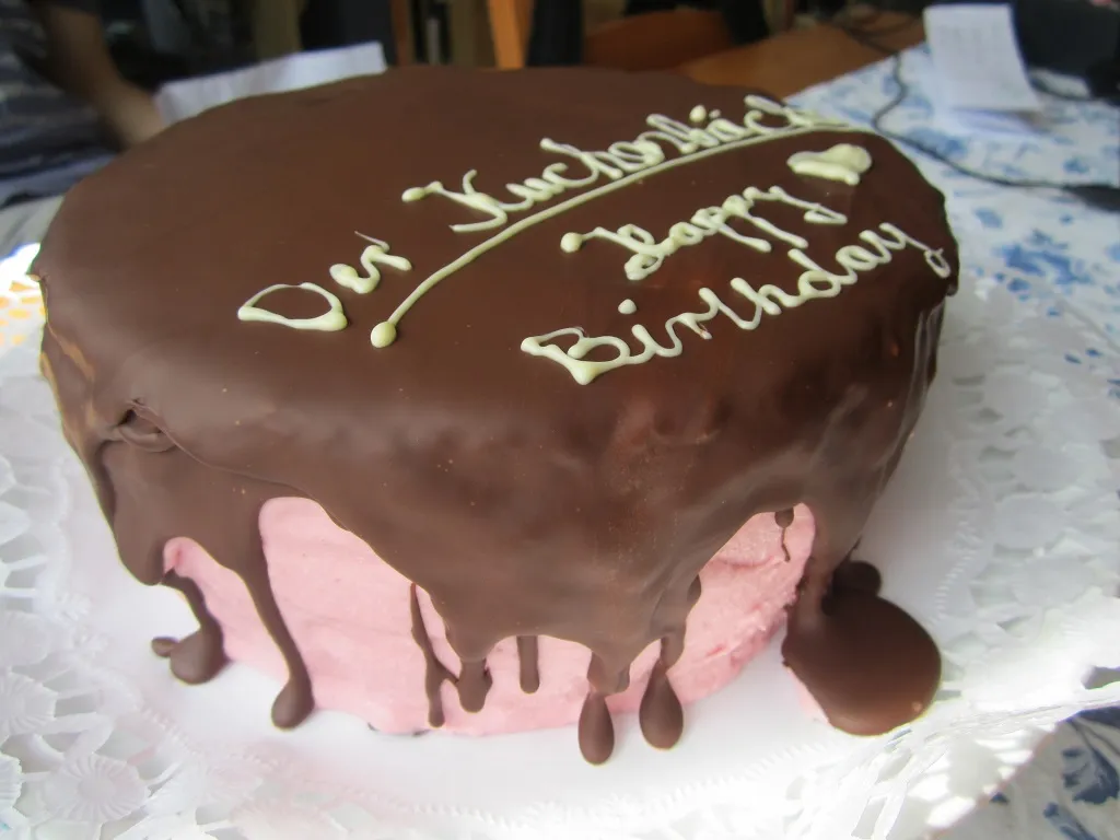 Nahaufnahme einer Geburtstagstorte, verziert mit der Aufschrift &quot;HAPPY BIRTHDAY&quot; aus weißer Schokolade