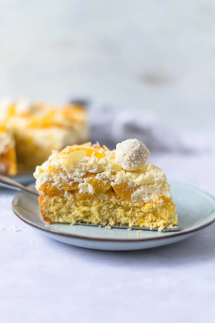 Nahaufnahme einer Pfirsich-Maracuja-Raffaelo-Torte mit glatt gestrichener Sahnecreme und Rand