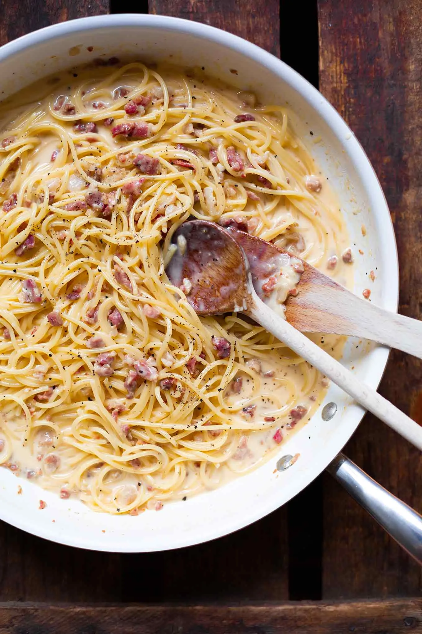 Nahaufnahme einer Portion einfacher Spaghetti Carbonara mit geriebenem Parmesan und knusprigem Speck.
