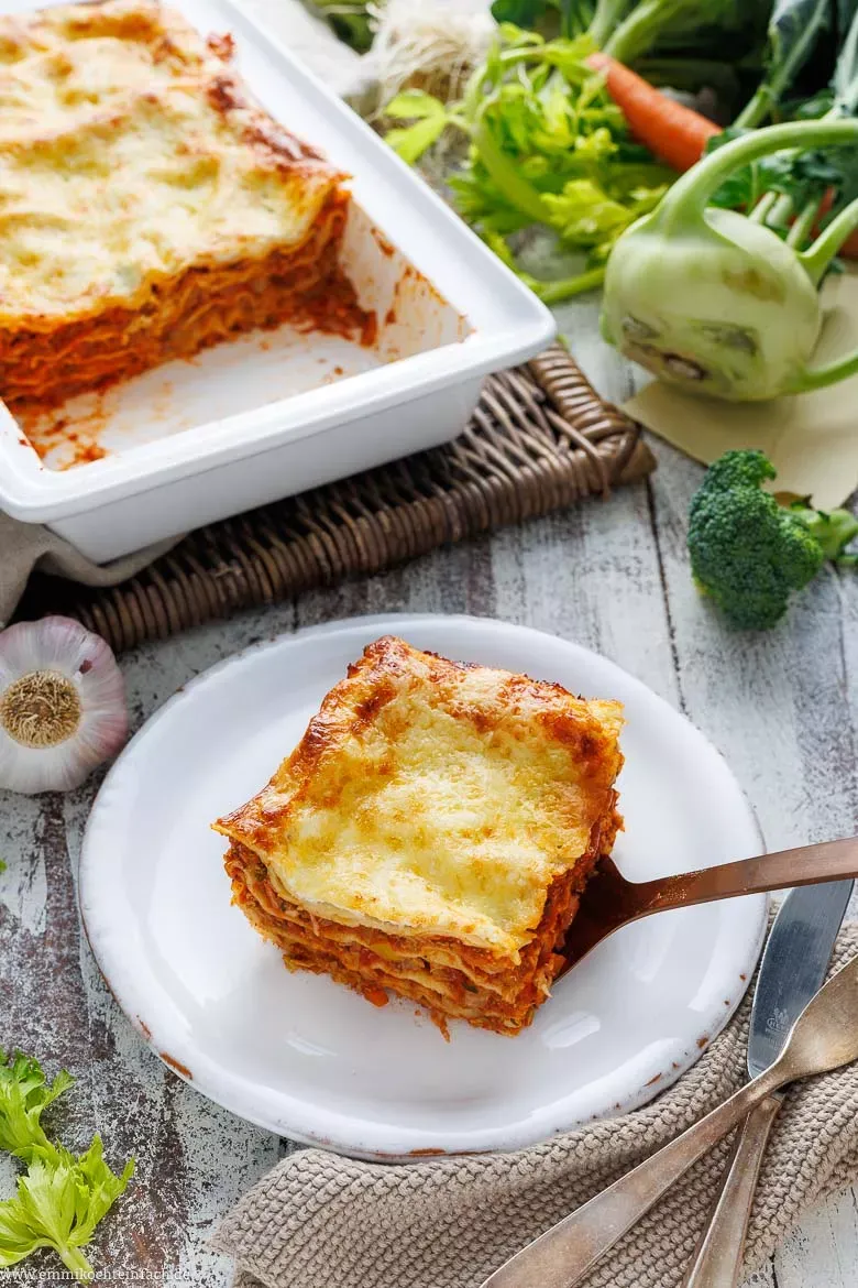 Nahaufnahme einer Portion vegetarischer Lasagne mit frischem Gemüse, servierfertig