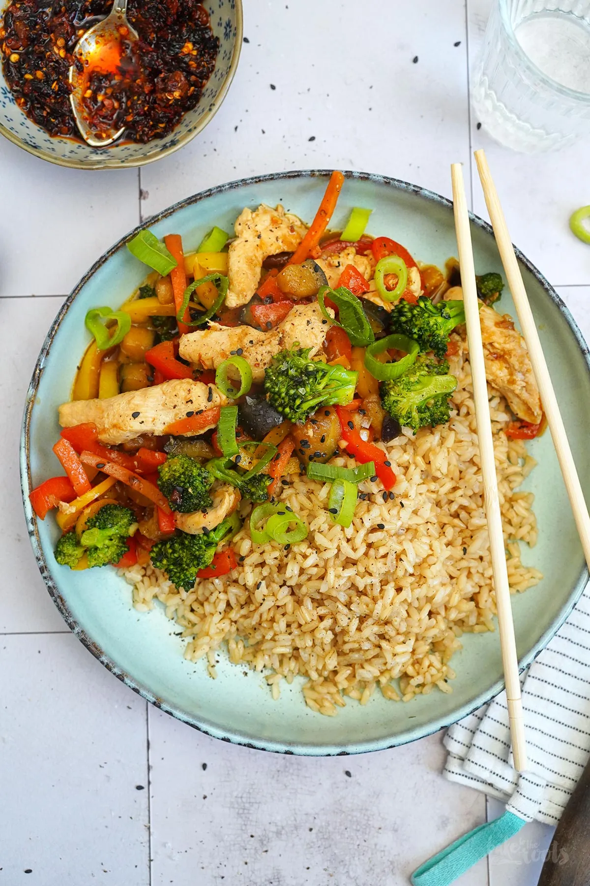 Nahaufnahme einer Portion Wok Gemüse mit Hähnchen und Reis, bereit zum Genießen mit Stäbchen