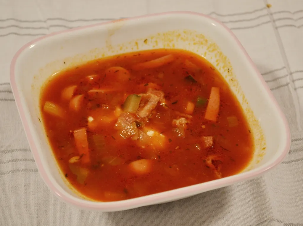 Nahaufnahme einer Soljanka-Suppe mit frischem Dill und Petersilie garniert.