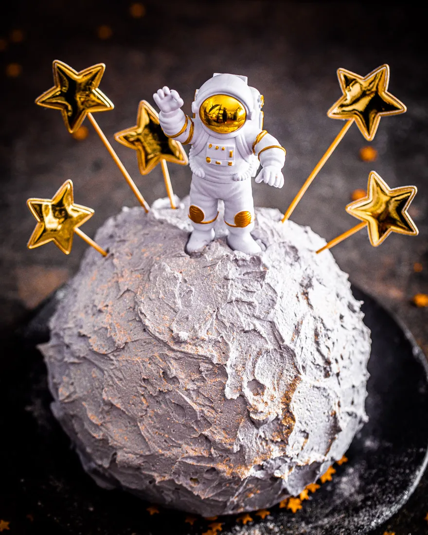 Nahaufnahme eines Astronauten auf einem grau besprühten Mondkuchen