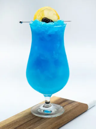 Nahaufnahme eines Blue Lagoon Cocktails im Glas mit Eis und Garnitur