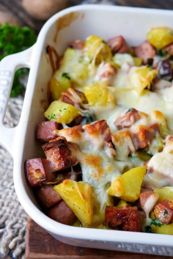 Nahaufnahme eines dampfenden Leberkäse-Auflaufs mit Kartoffeln und geschmolzenem Käse, ideal für ein deftiges Familienessen