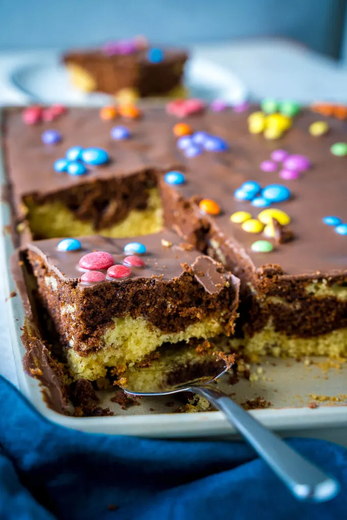 Nahaufnahme eines einfachen Paw Patrol Blechkuchens mit Schokoglasur und bunten Smarties-Pfoten, perfekt für den Kindergeburtstag.