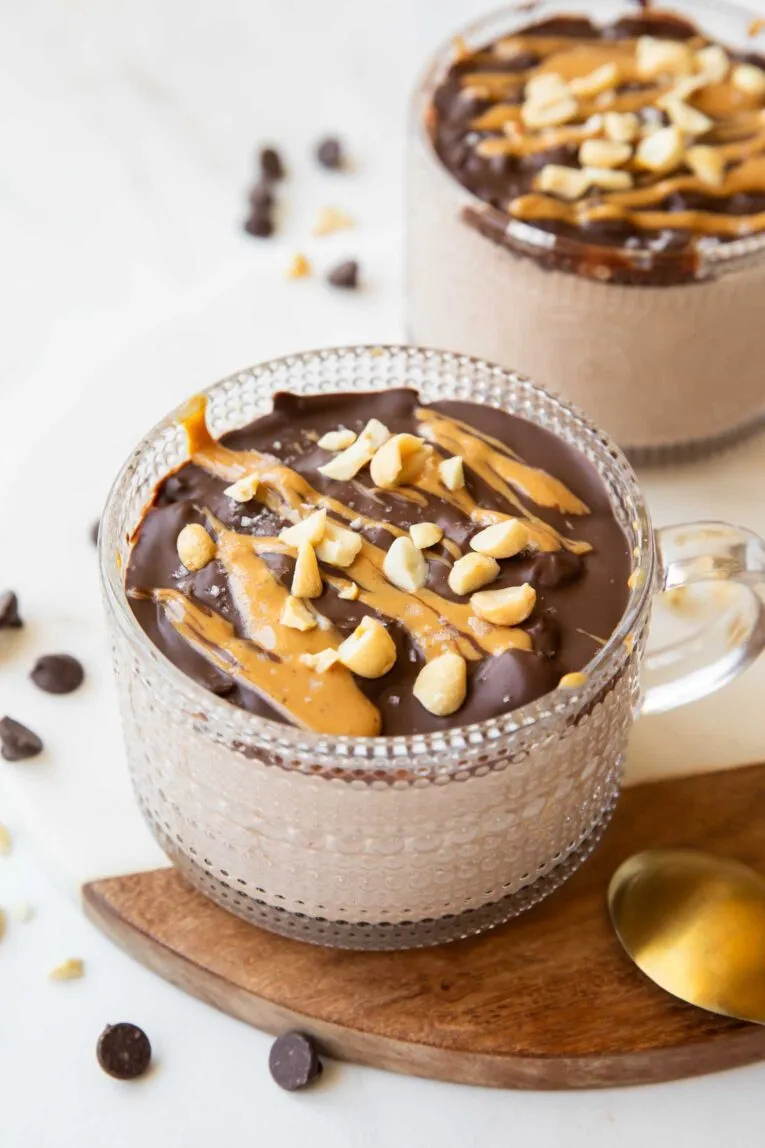 Nahaufnahme eines Glases Snickers Overnight Oats mit Schokoladenüberzug und Nüssen, aus einer schrägen Perspektive.