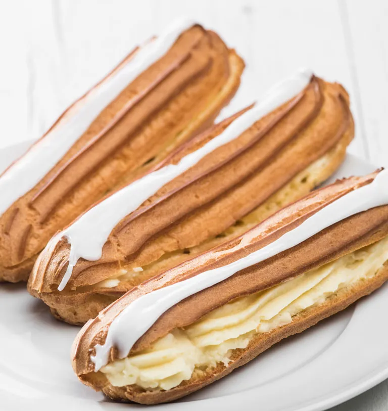 Nahaufnahme eines köstlichen Vanille-Eclairs mit cremiger Füllung, perfekt für den Nachmittagskaffee