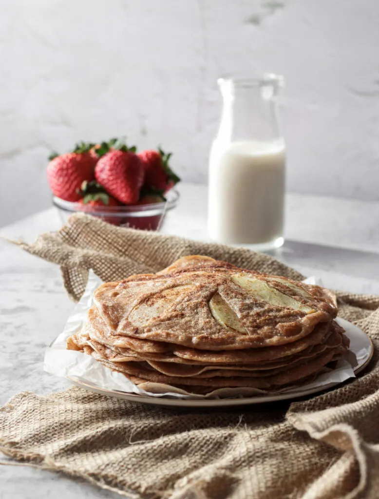 Nahaufnahme eines Stapels Apfelpfannkuchen mit Apfelscheiben, Zimt und Zucker, perfekt für ein veganes Frühstück