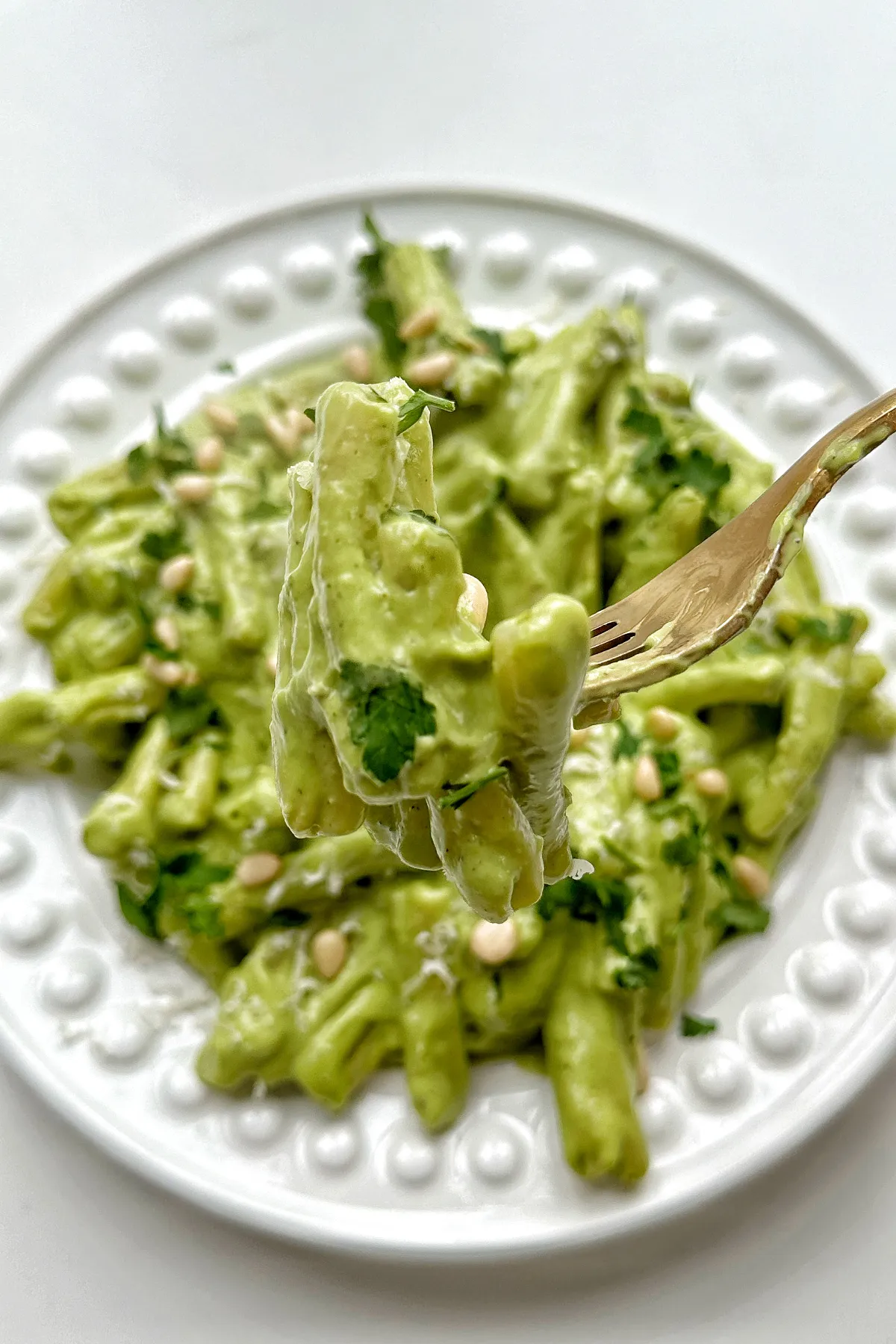 Nahaufnahme von Avocado Pesto Pasta, kunstvoll mit einer Gabel aufgenommen.