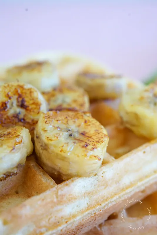 Nahaufnahme von Belgischen Waffeln mit karamellisierten Bananen und Ahornsirup
