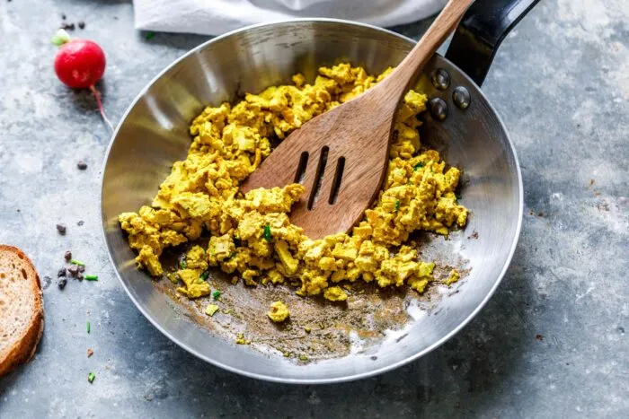 Nahaufnahme von cremigem veganem Rührei in einer Pfanne, mit Sojajoghurt verfeinert für die perfekte Konsistenz.