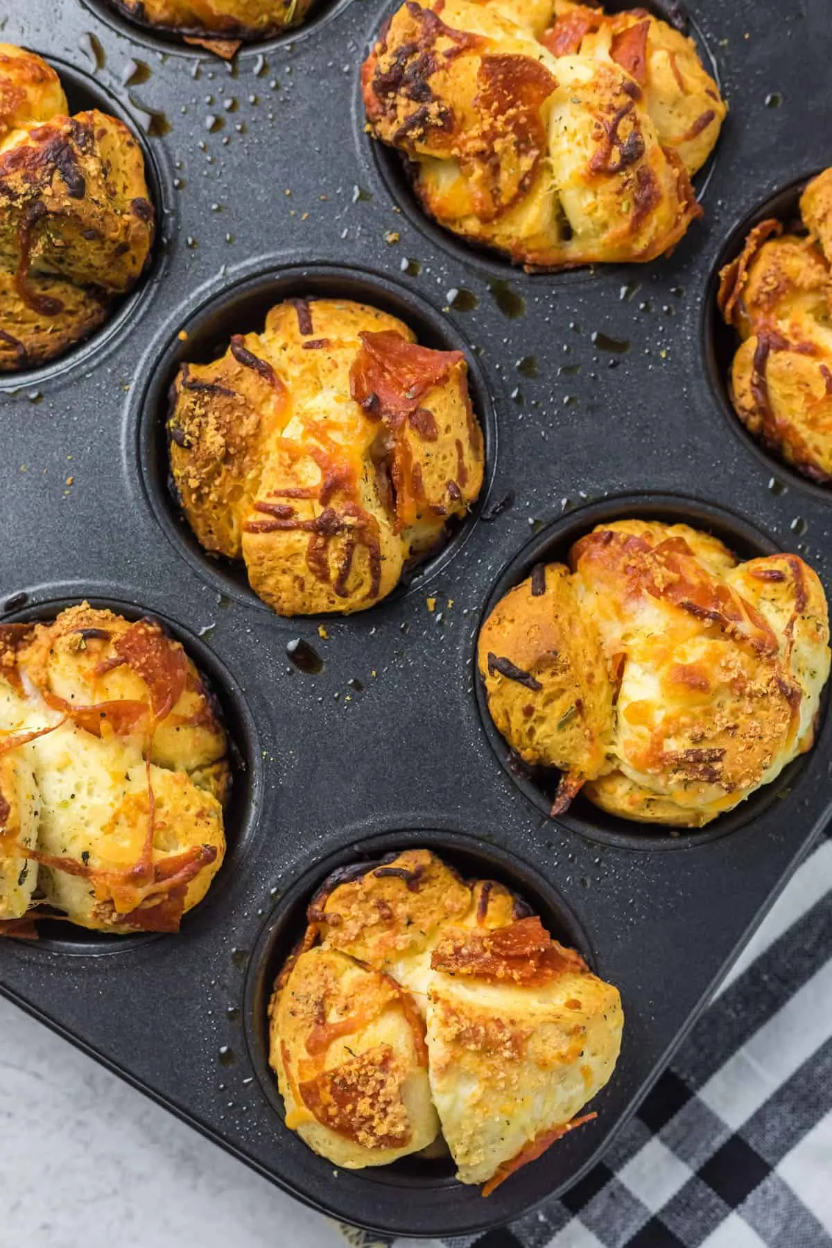 Nahaufnahme von fertig gebackenen Pizza Muffins in einem Muffinblech, goldbraun und leicht aufgegangen.