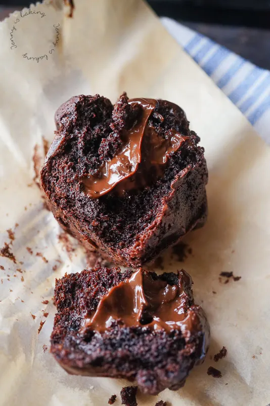 Nahaufnahme von frisch gebackenen Schoko Muffins mit flüssiger Schokoladenfüllung, präsentiert auf einem Backblech, die den unwiderstehlichen Genuss und die saftige Textur hervorhebt