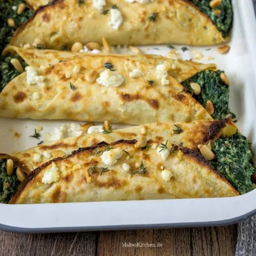 Nahaufnahme von frisch gebackenen und leicht gratinierten gefüllten Pfannkuchen mit Spinat-Ricotta-Füllung