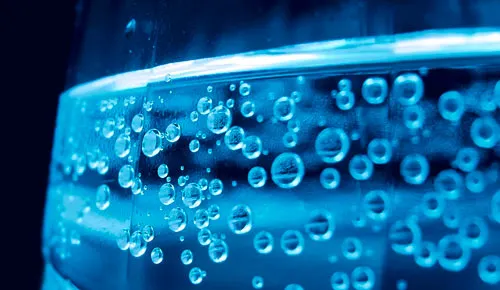 Nahaufnahme von Mineralwasserflaschen, die auf einem Regal in einem Getränkemarkt stehen.