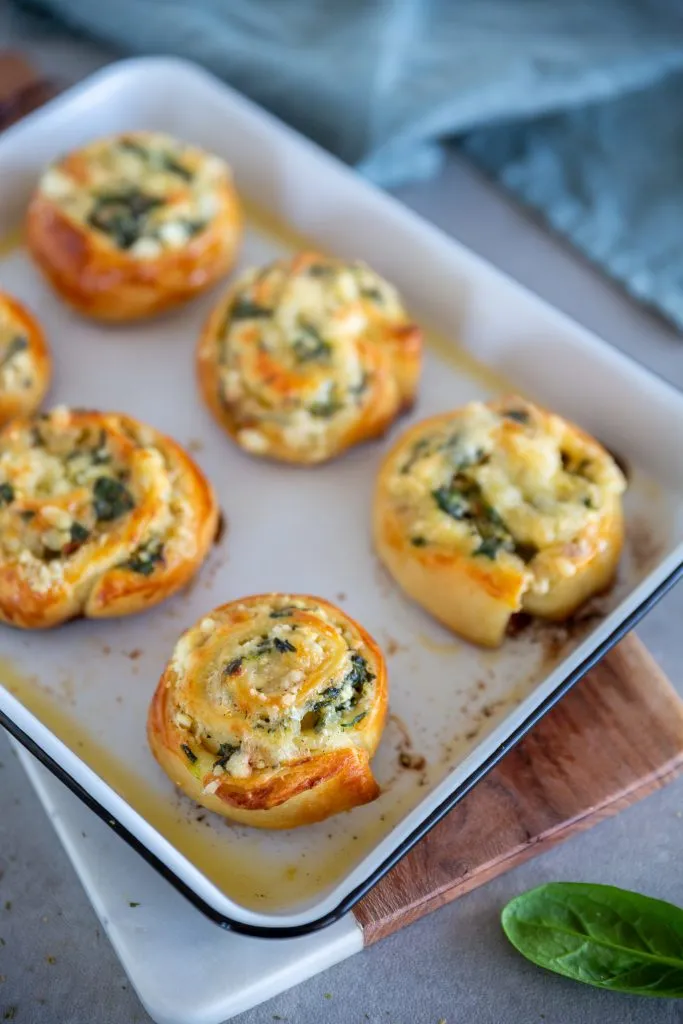 Nahaufnahme von saftigen Feta-Spinat-Pizzaschnecken auf einem Backblech, bereit zum Servieren als schnelles Fingerfood