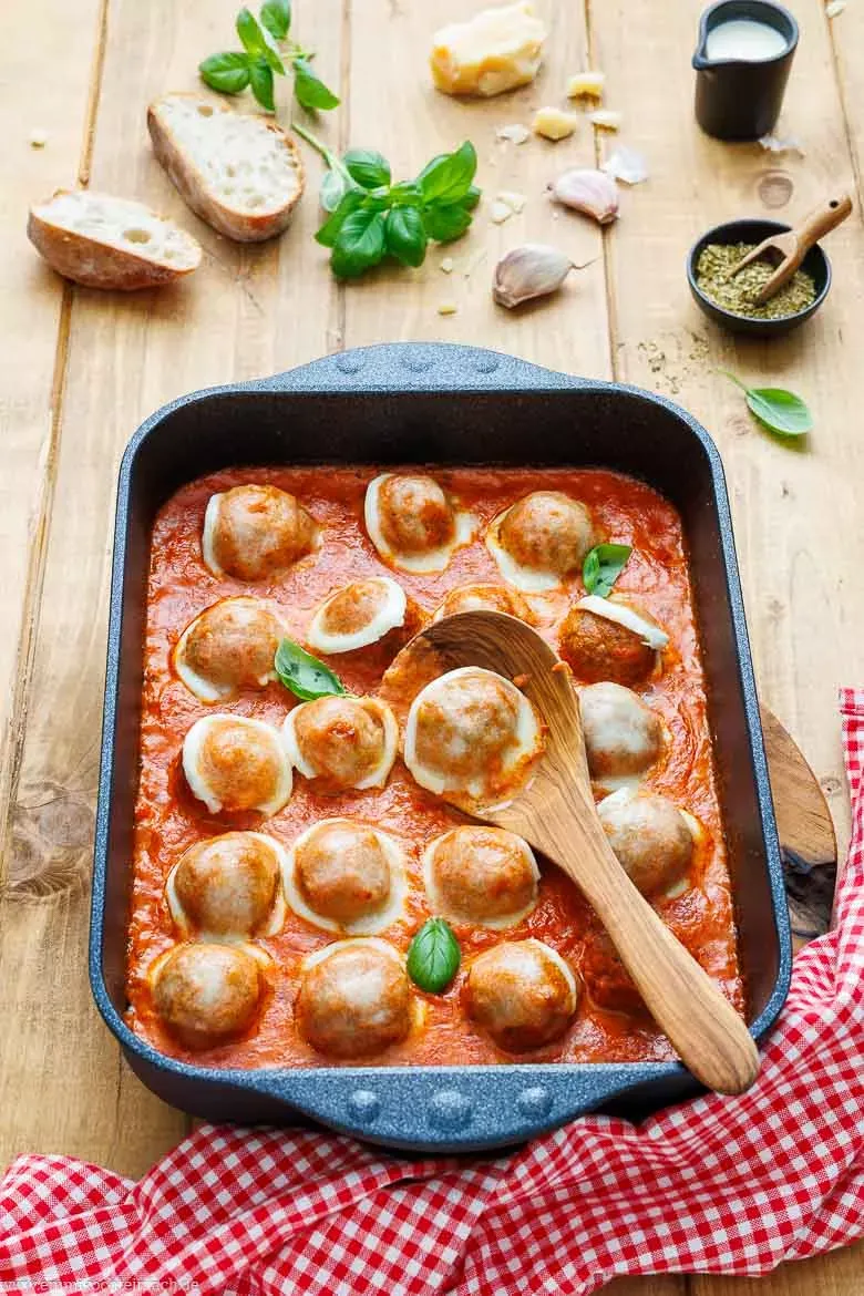 Nahaufnahme von saftigen Hackbällchen, bedeckt mit fruchtiger Tomatensoße und geschmolzenem Büffelmozzarella