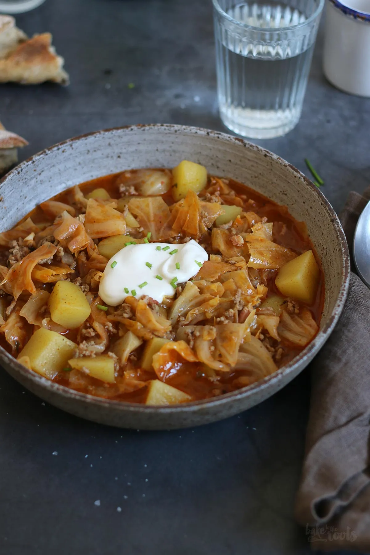 Nahaufnahme von Schichtkohl mit Hackfleisch und Kartoffeln, appetitlich angerichtet mit frischen Kräutern