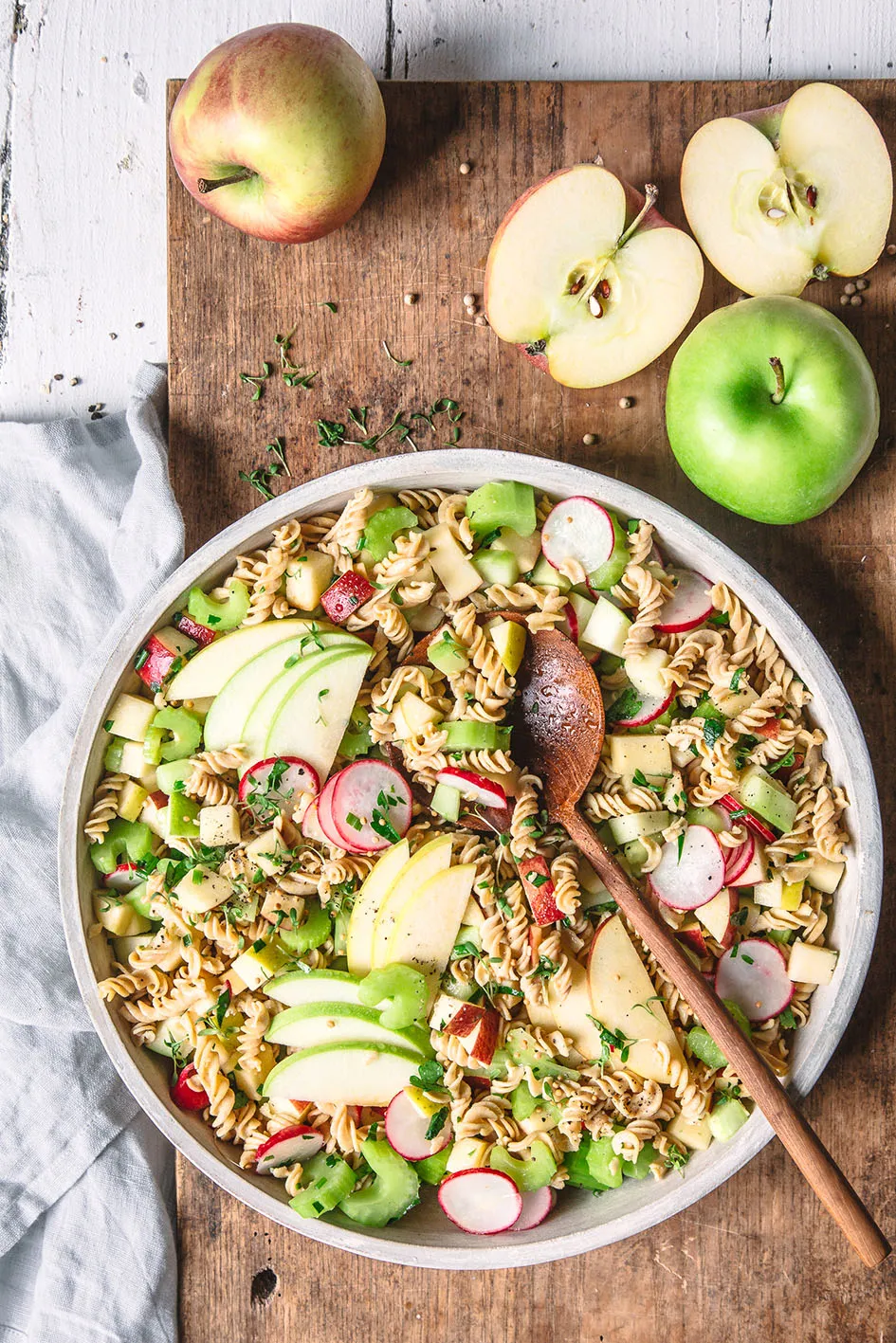 Nudelsalat mit Apfel auf Holzbrett und Kochlöffel