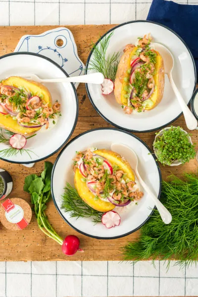 Ofenkartoffel mit frischen Nordseekrabben, cremigem Kräuterquark und Radieschen, fertig zum Servieren.