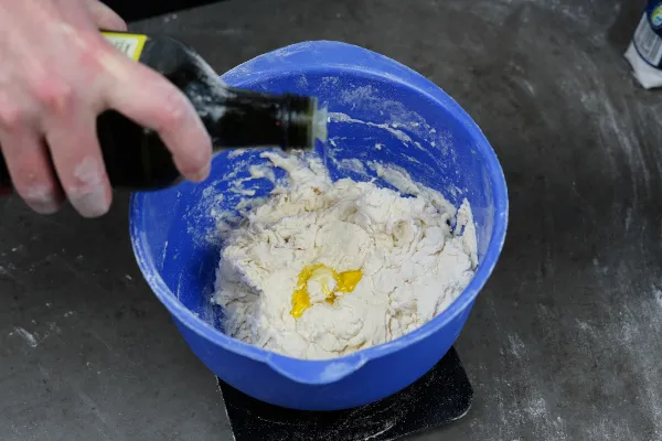 Olivenöl und Salz zum Pizzateig hinzufügen