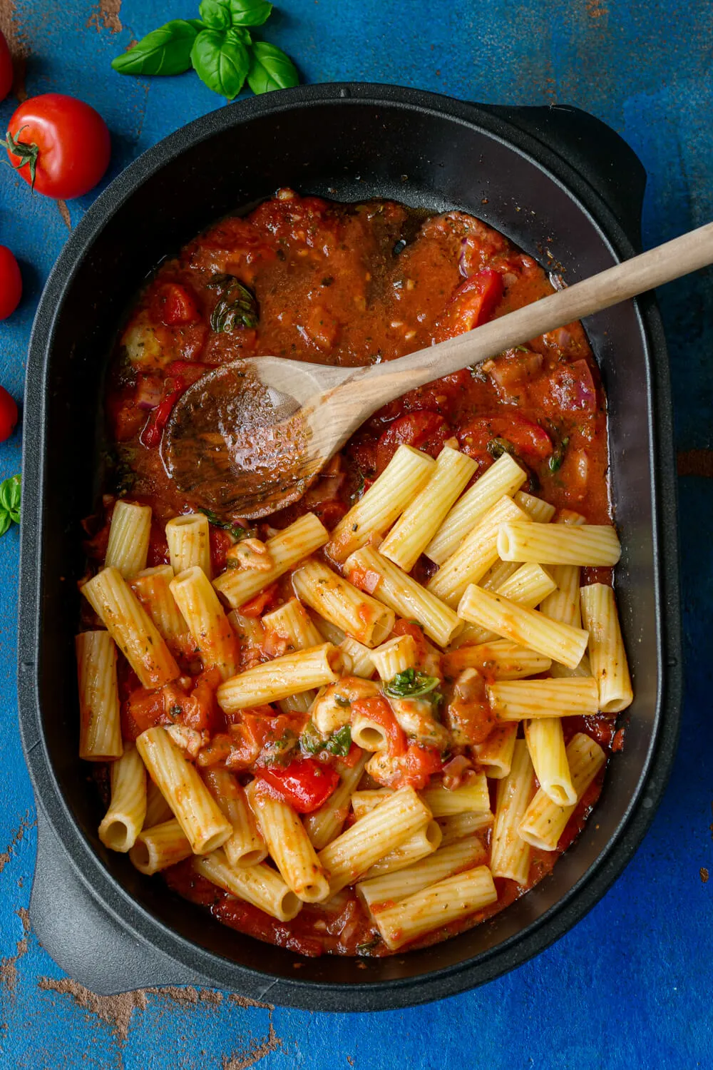 omaten-Mozzarella-Soße mit Basilikum und Nudeln in der Auflaufform. Alternative Text: Hausgemachte Tomaten-Mozzarella-Soße aus dem Ofen, verfeinert mit frischem Basilikum, serviert mit Nudeln in einer Auflaufform, ein einfaches und aromatisches Mittagessen.