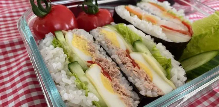 Onigirazu (Reis-Sandwiches) in einer Bento-Box mit Gemüse