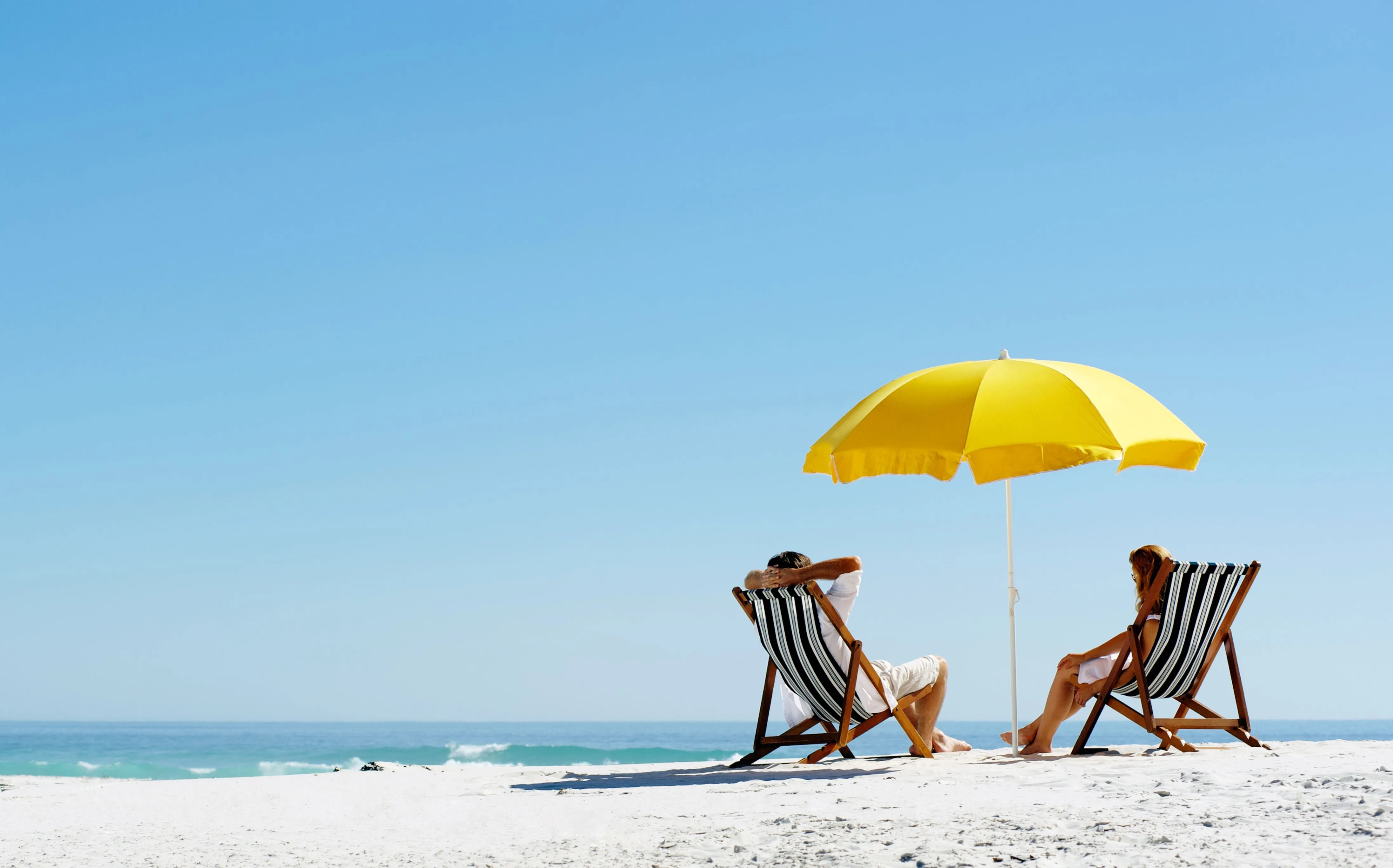 Paar entspannt am Strand unter Sonnenschirm