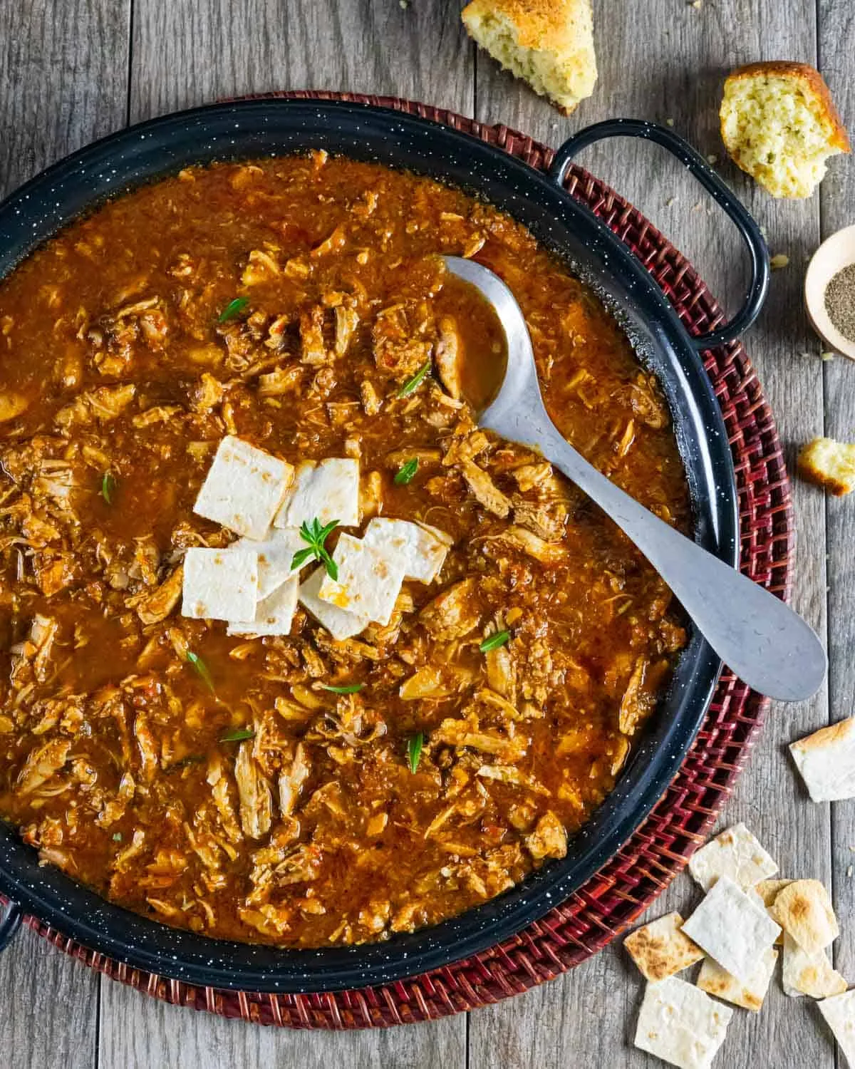 Paella-Pfanne mit spanischer Suppe, Tortilla-Quadraten in der Mitte und einem Servierlöffel.