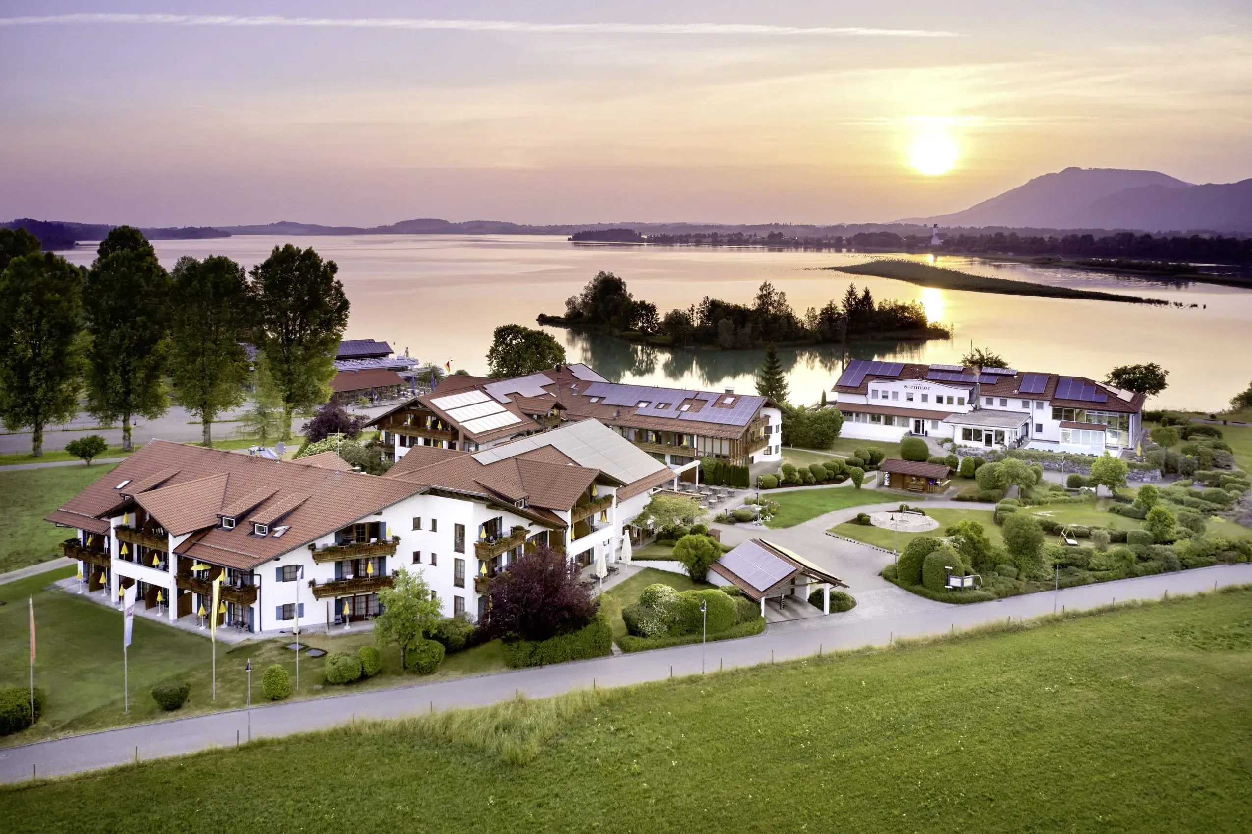 Panoramablick auf das Hotel Sommer bei Sonnenuntergang über dem Forggensee, unterstreicht die idyllische Lage dieses Hundehotels in Füssen.