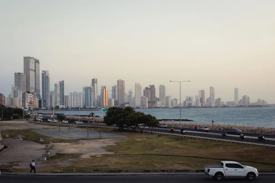Panoramablick auf die Skyline einer Küstenstadt bei Sonnenuntergang mit Hochhäusern und ruhigem Meer im Vordergrund