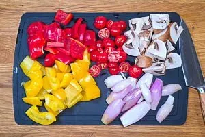 Paprika, Kirschtomaten, Champignons und Schalotten für die Antipasti vorbereiten