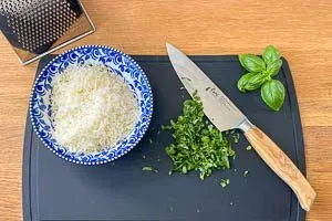 Parmesan reiben, Basilikum zerkleinern.