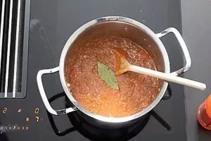 Passierte Tomaten und Lorbeerblatt zur Bolognese-Soße hinzufügen