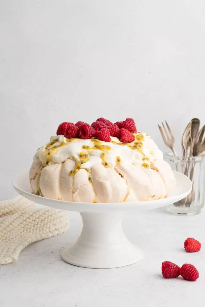 Passionsfrucht mit Schlagsahne, Passionsfrucht und Himbeeren auf Kuchenplatte mit Gabeln