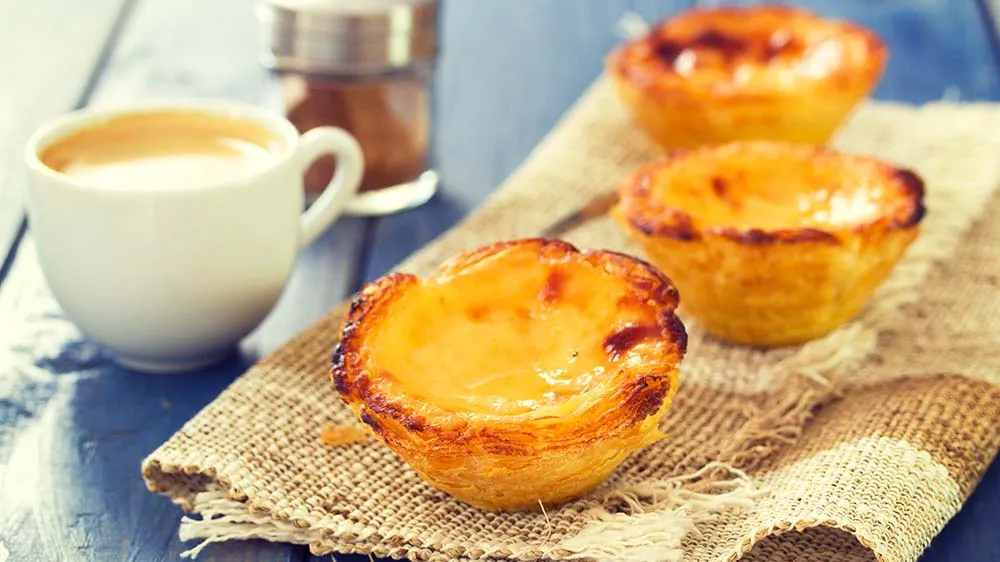 Pasteis de Nata, portugiesische Blätterteigtörtchen, serviert mit Kaffee auf einem Tuch