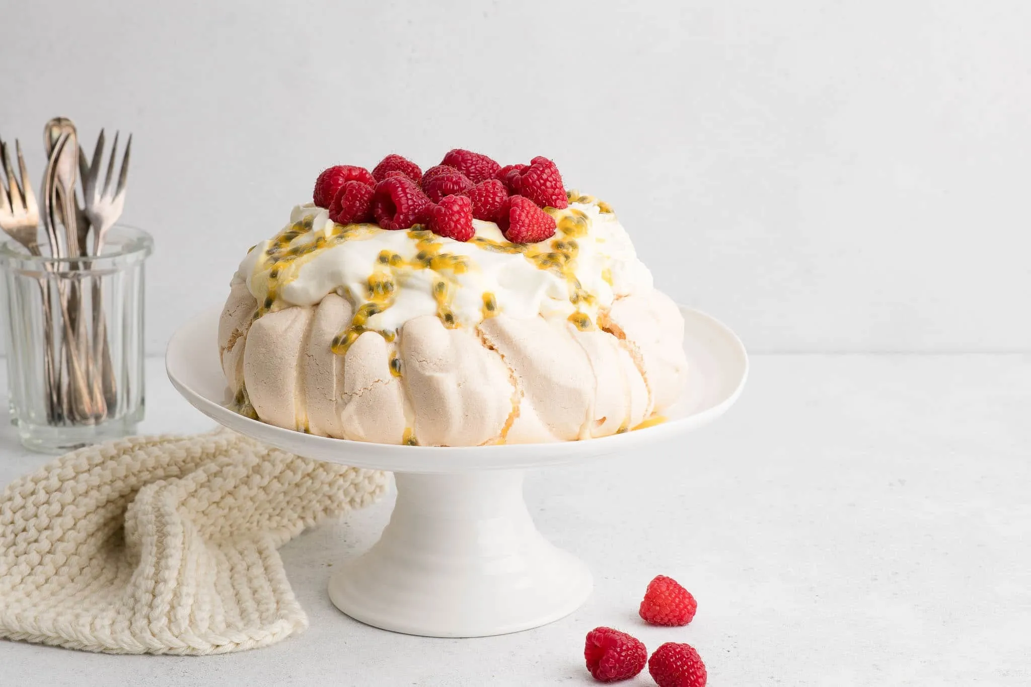 Pavlova mit Sahne und Passionsfrucht auf weißer Kuchenplatte